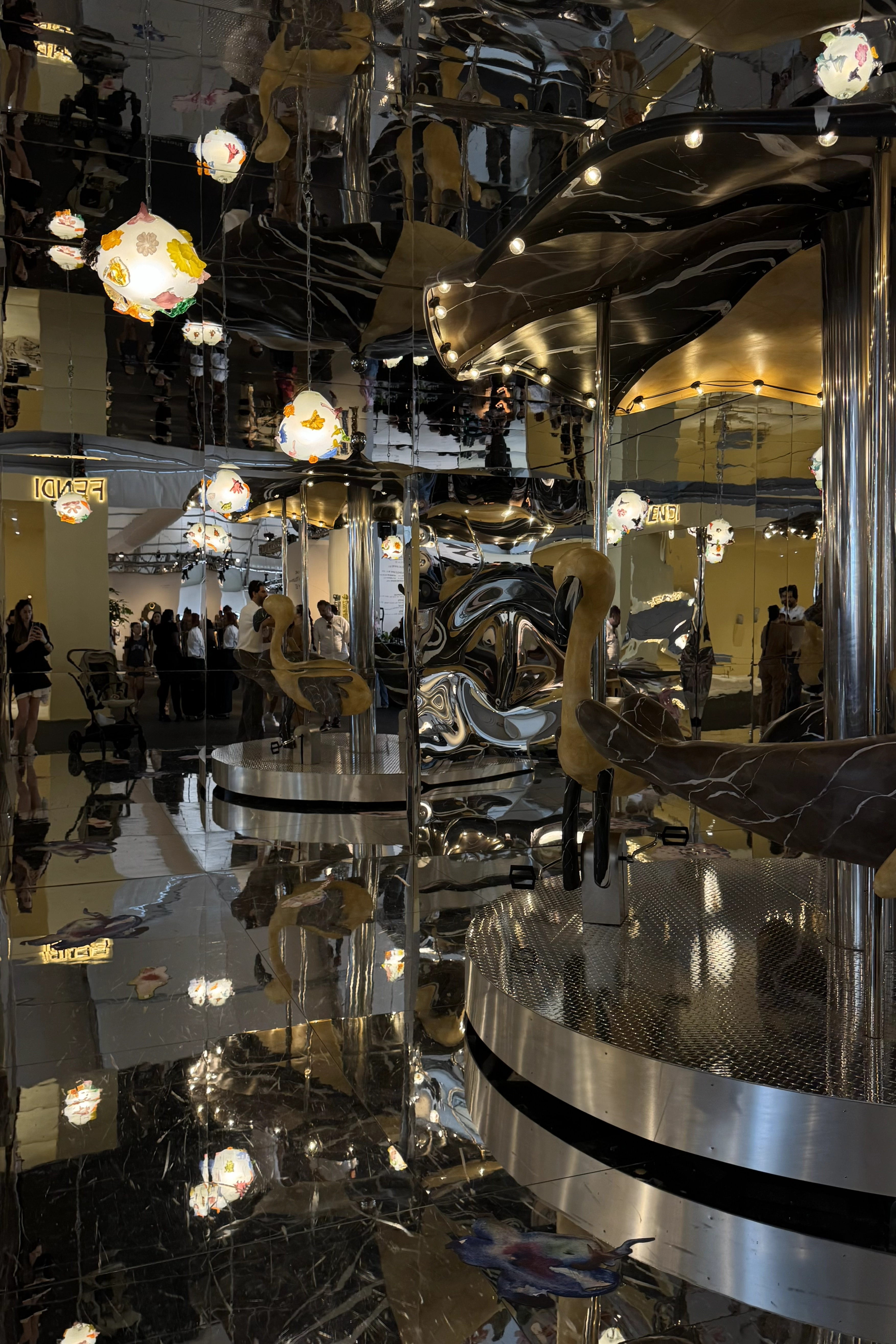 Immersive mirrored design installation with sculptural seating and reflective surfaces at a contemporary exhibition.