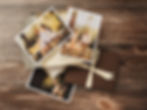 Fine Art Prints on a wooden table, featuring a couple with a child outdoors. Warm, sunny tones and a brown envelope with a ribbon.