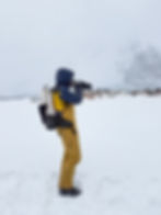 Max in winter gear photographs penguins on snowy terrain, surrounded by misty mountains. The mood is serene and focused.