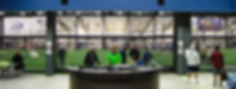Several people standing at a media table inside of an indoor multi-sports complex