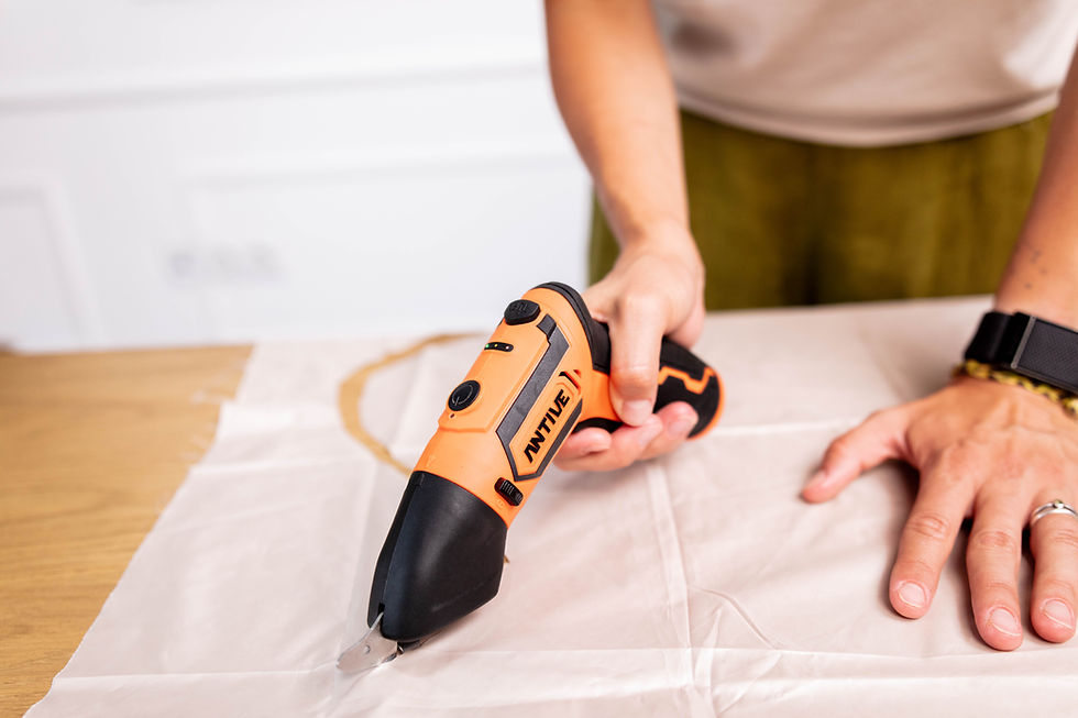 The electric fabric cutter cuts a piece of white fabric.