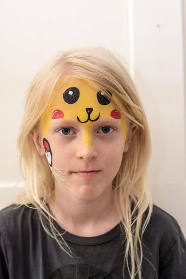 Ein blonder Knabe, welcher von Jiovanna mit einem Pikachu-Sujet geschminkt wurde
