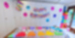 Bunt dekorierter Geburtstagstisch mit farbigen Servietten, Bastelmaterial und einer "Happy Birthday"-Girlande an der Wand