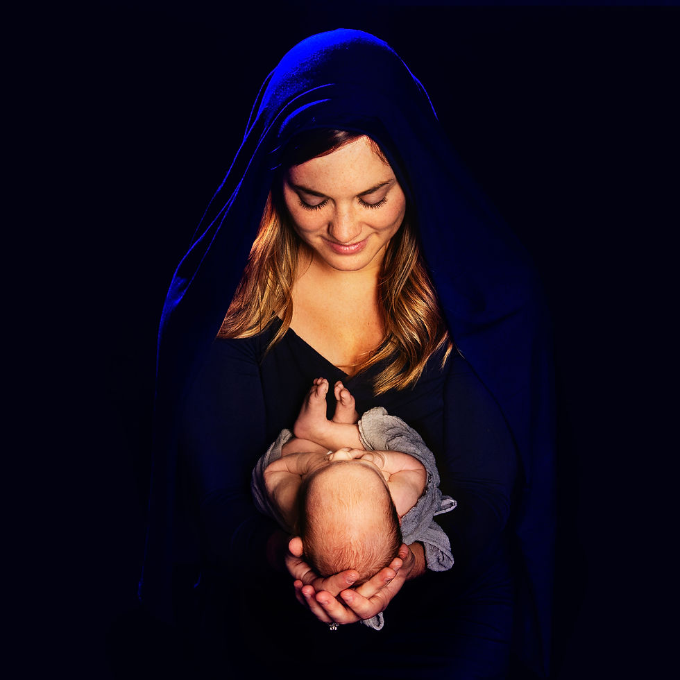 A sheep by a manger with a baby.