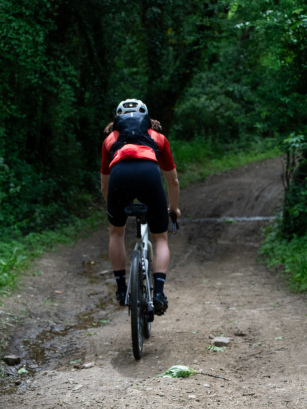 Vue latérale d'un cycliste gravel en pleine réparation sur un chemin forestier