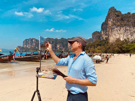 Marc Dalessio painting on a beach.