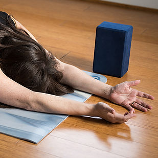 Yoga student in child's pose arms outstretched, palms facing up.