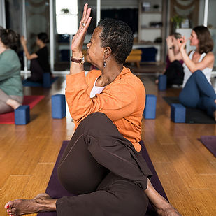 Mature woman in a seated spinal twist at Three Birds Yoga Studio.