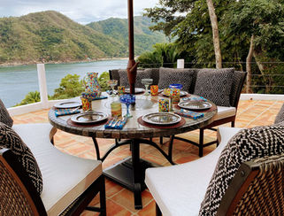 Terrace dining table with cushioned seating overlooking the bay