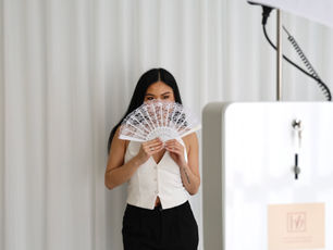 A woman hlding a white fan over her face while using a photobooth