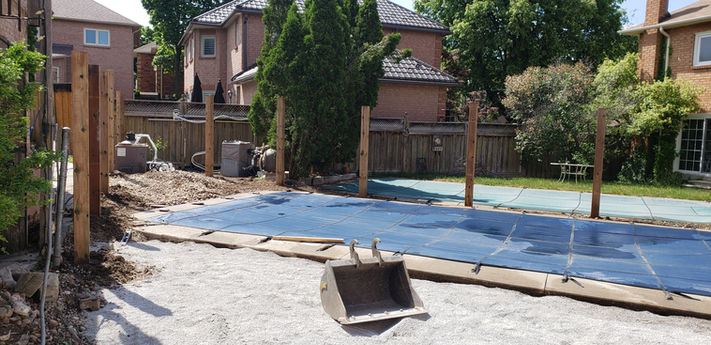 Backyard project under construction, excavator bucket, blue tarp.