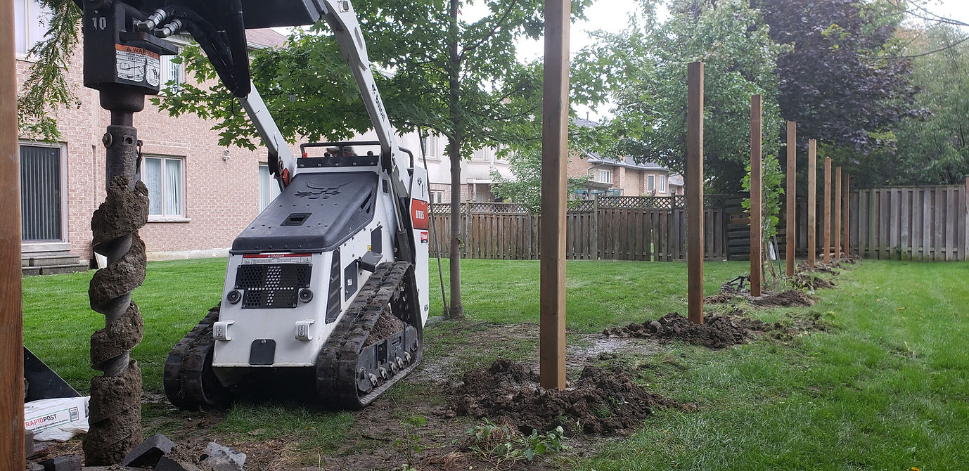 Mini-excavator installing posts for Barrie fence construction