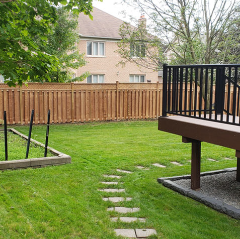 Backyard deck with dark aluminum railings, stone path, and green grass