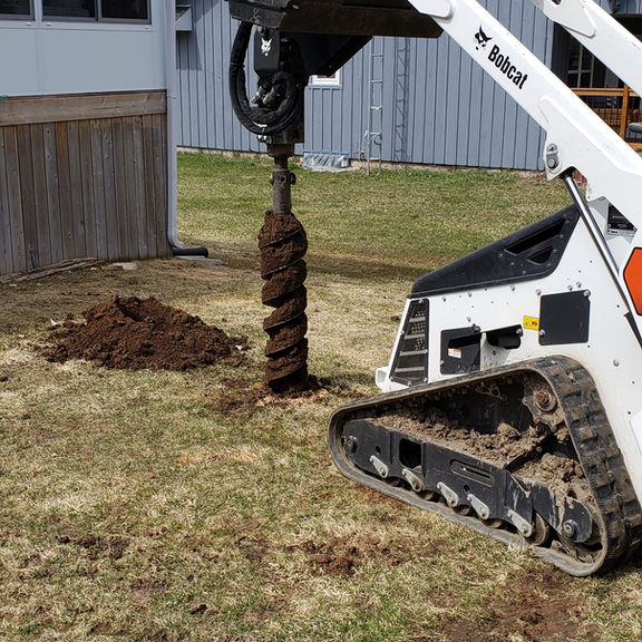 Bobcat auger drilling post hole for Barrie fence construction
