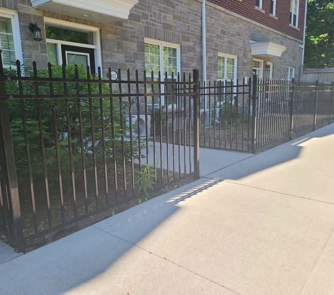 Black metal fence along sidewalk by Ontario fence contractors