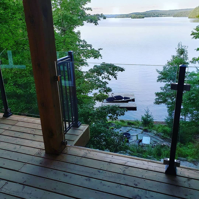 Wooden deck with aluminum glass railings overlooking a lake