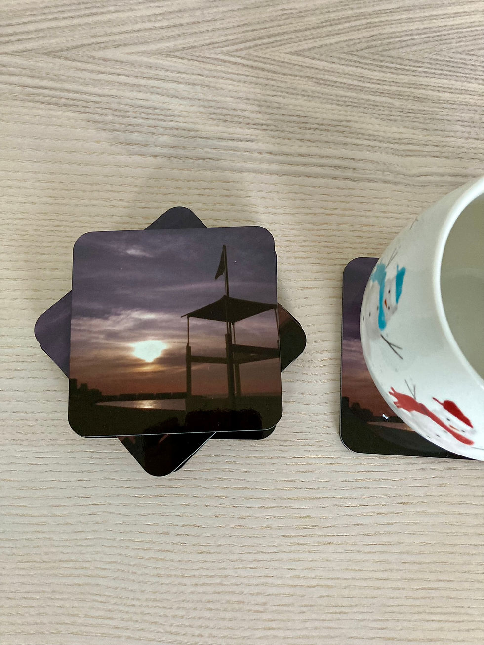 Thumbnail: Sunset photo coasters on the top of each other with one coaster under the mug, on the table