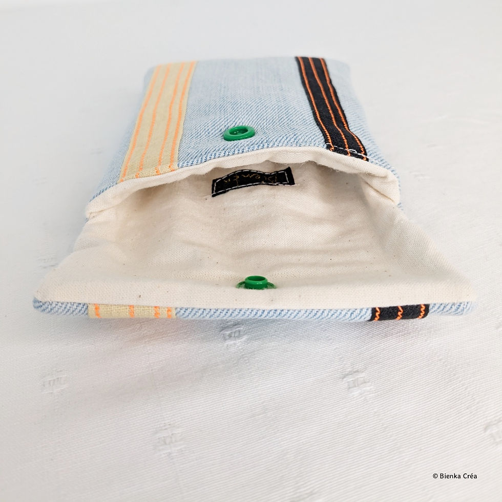 Miniature : Vue de l'intérieur d'une pochette molletonnée en jean bleu clair fermée par un bouton pression vert