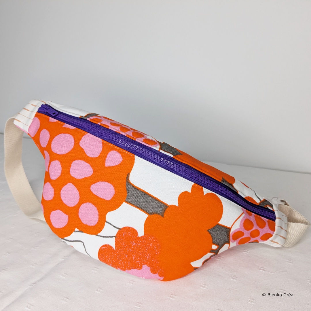 sac banane en coton molletonné et à motifs pops orange et rose fermé par un zip violet