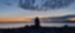 A sunset beach view over a mound of small stones.