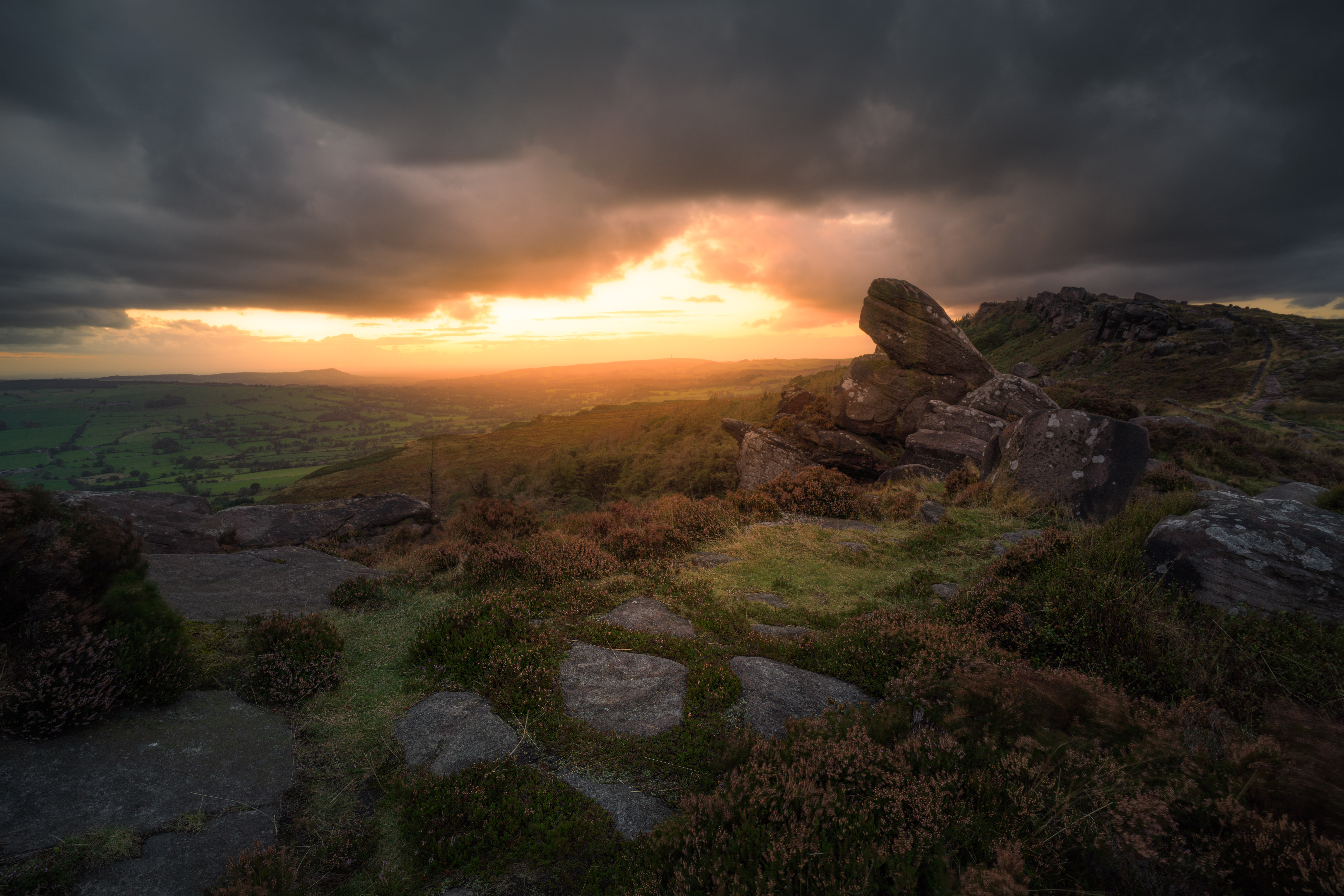 The dramatic gritstone rock formations and sweeping valleys of the Peak District at sunrise.