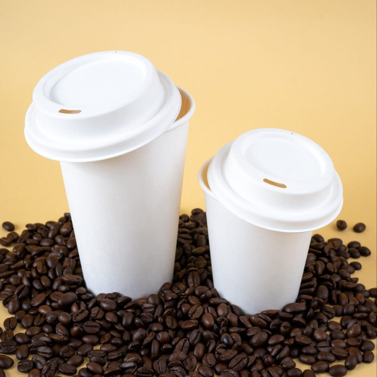 Two white coffee cups on whole coffee beans