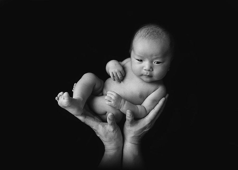 Newborn baby in daddy's hands, fine art black and white photographer near Andover