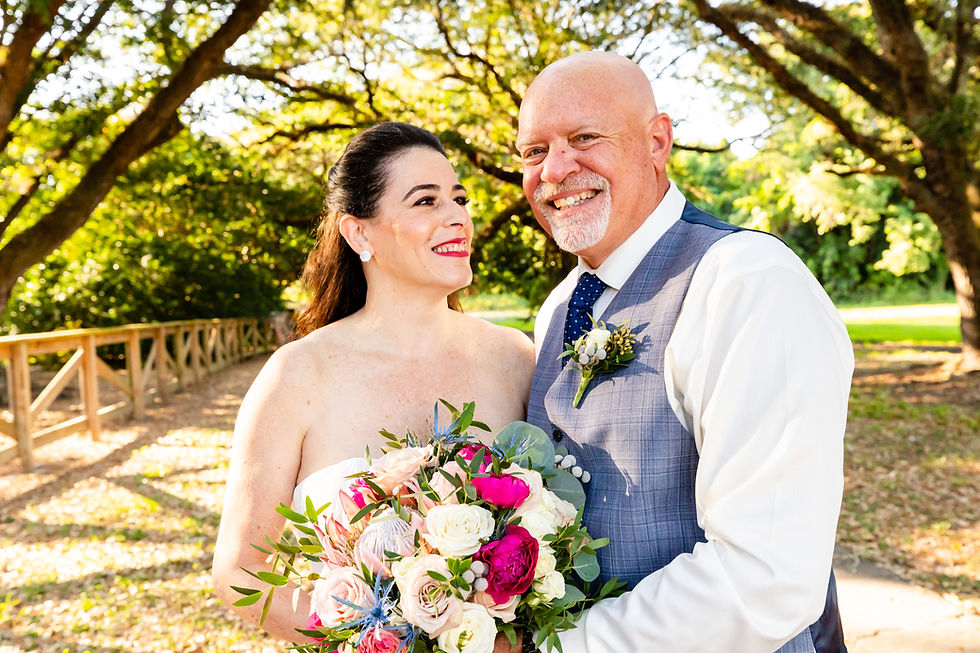 Cincinnati wedding photographer captures image of husband and wife smiling holding a bouquet of flowers in the park.