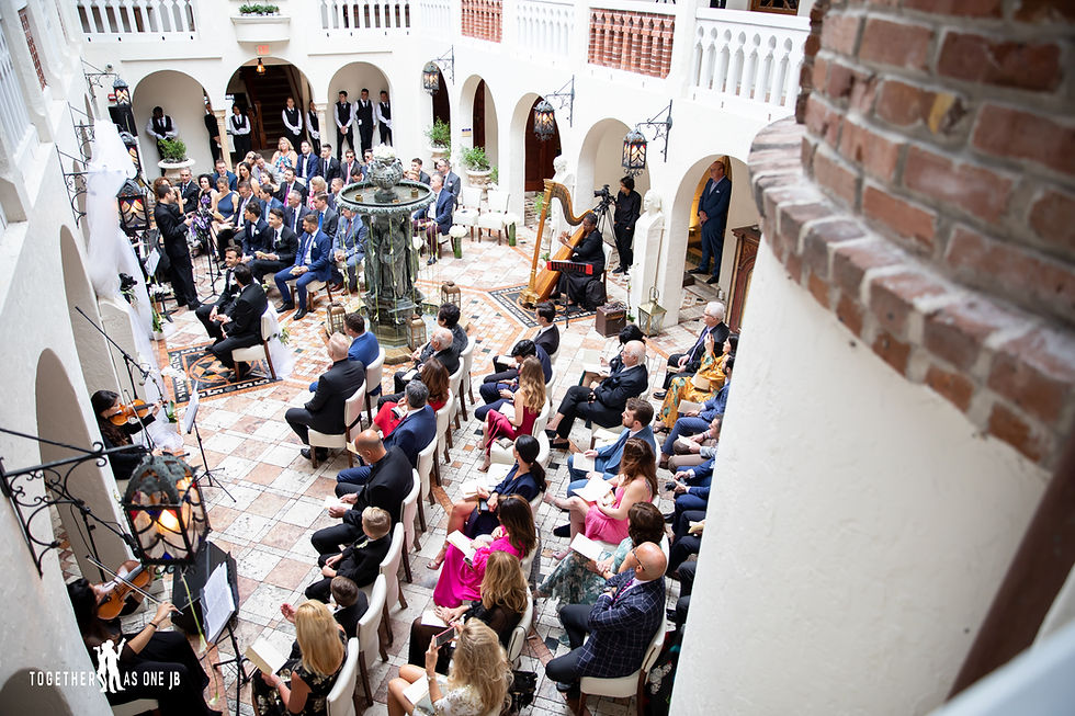 Wedding guests and couple seated listening to orchestra during wedding ceremony in outside courtyard at the Villa Casa Casuarina