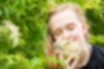 Cincinnati family photographer captures portrait of smiling girl smelling white flower closing her eyes.