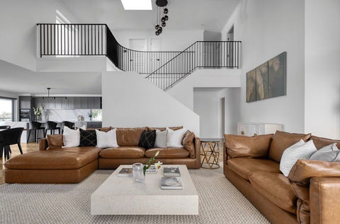 Modern home interior: leather sofas, marble coffee table, staircase