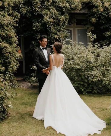 a bride and groom in their wedding clothes holding hands outdoors