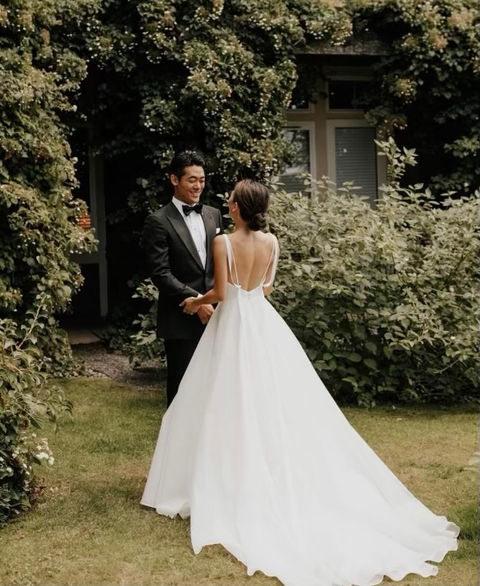a bride and groom in their wedding clothes holding hands outdoors