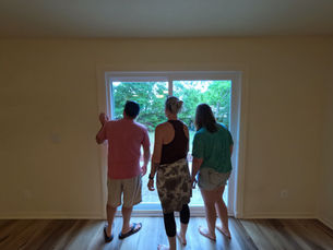 Home buyers standing inside an empty living room looking out a sliding glass door, representing a home showing and real estate buying process in Fort Walton Beach, FL.