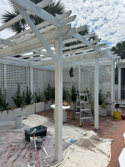2T Touch-ups: A white pergola in progress with painting materials, enhancing the outdoor space with a clean and refreshed look.