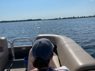 Guest relaxing on a pontoon boat while cruising calm Destin waters under a clear blue sky, enjoying a private pontoon cruise along the Emerald Coast.