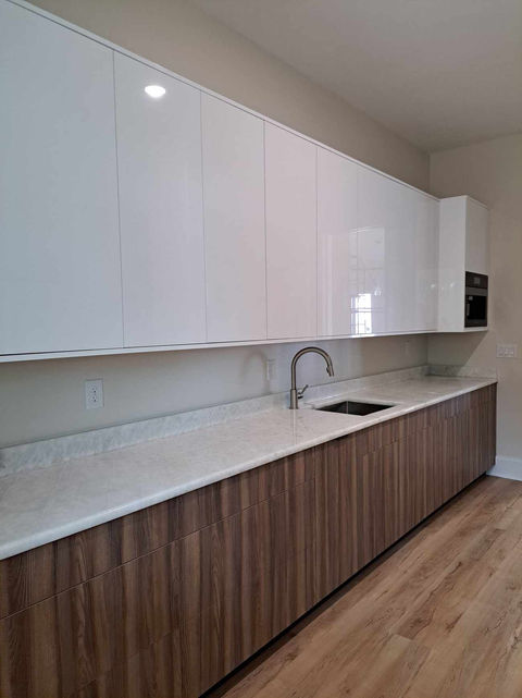Extended view of the custom kitchen in Pensacola, FL, highlighting the wood-grain and white cabinetry, modern appliances, and an elegant open layout.