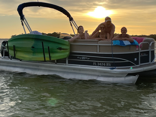 Family enjoying a sunset pontoon boat cruise in Destin, FL on the Emerald Coast, cruising calm waters during a private captained sunset boat tour.
