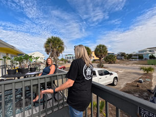 Caron Realtor meeting with a homeowner on a coastal balcony in Fort Walton Beach, FL, discussing real estate services and local property values.