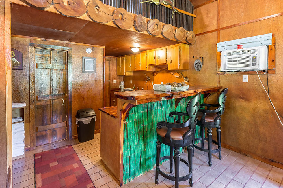Rustic cabin interior with full kitchen, breakfast bar seating, and wood accents at a cabin rental in Escambia County near the Blackwater River.