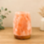 Pink Himalayan salt lamp unlit on a wooden surface with soft neutral background and natural styling.