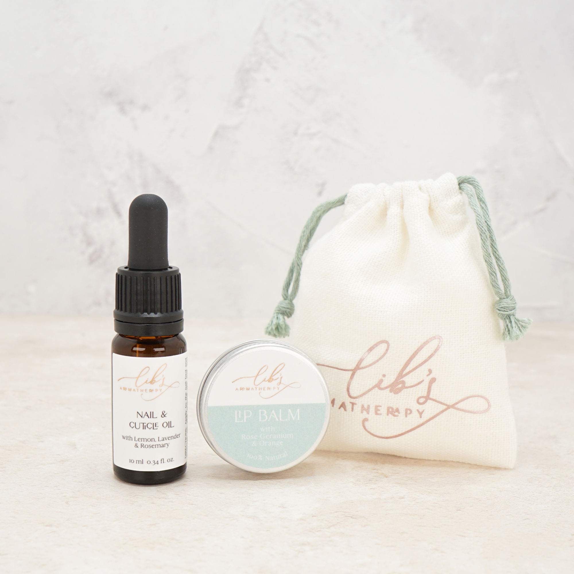 A nail oil and lip balm arranged next to a mini drawstring bag