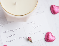 a valentines message, candle and pink chocolate hearts