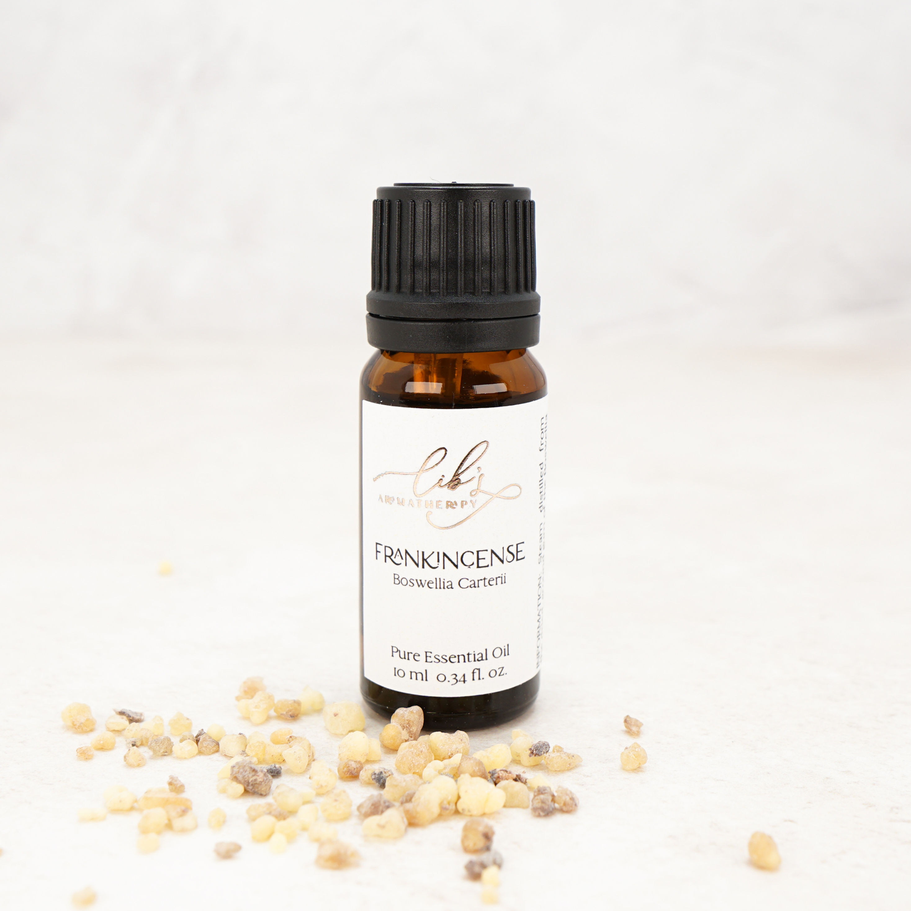 A bottle of essential oil with frankincense scattered around.