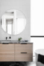 Modern bathroom renovation: round mirror, wood vanity, white tiles.