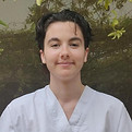 portrait photo d'Eris Siffre, iel a les cheveux courts, et porte une blouse d'ostéopathe