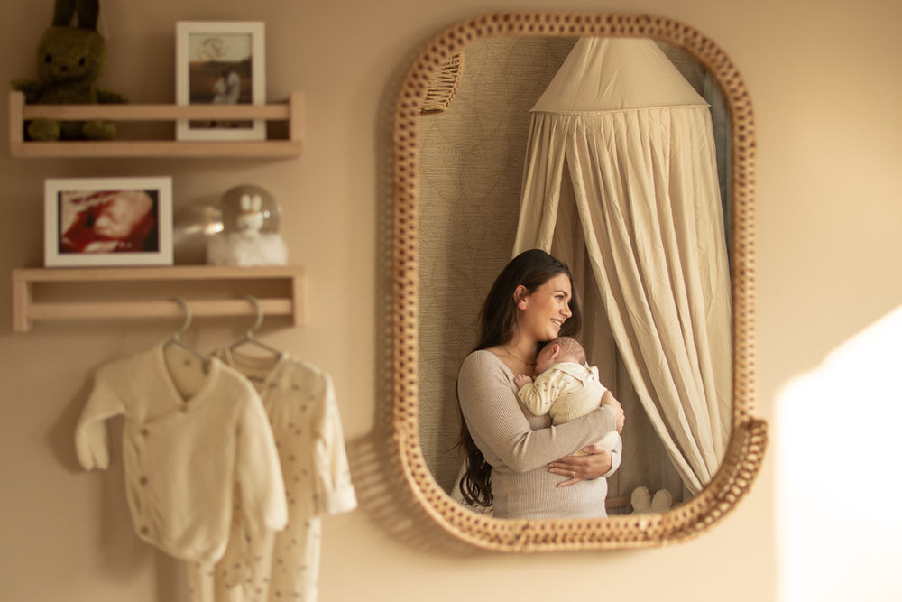 Moeder met pasgeboren baby weerspiegeld in babykamer