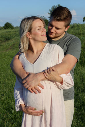 Zwangere vrouw en partner lachend tijdens fotoshoot buiten in Apeldoorn