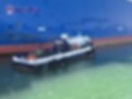 MaxiDive workboat with diving equipment moored beside a vessel during underwater inspection and cleaning operations.