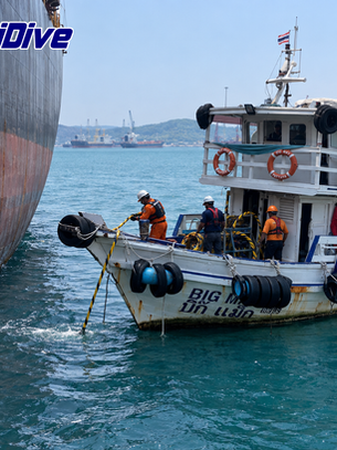 MaxiDive support boat alongside a commercial vessel, with crew handling a line on deck.